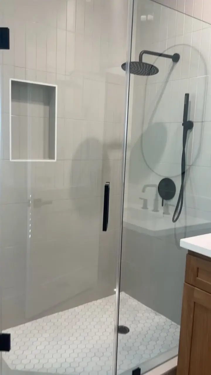 Corner glass shower with black fixtures in an ADU bathroom